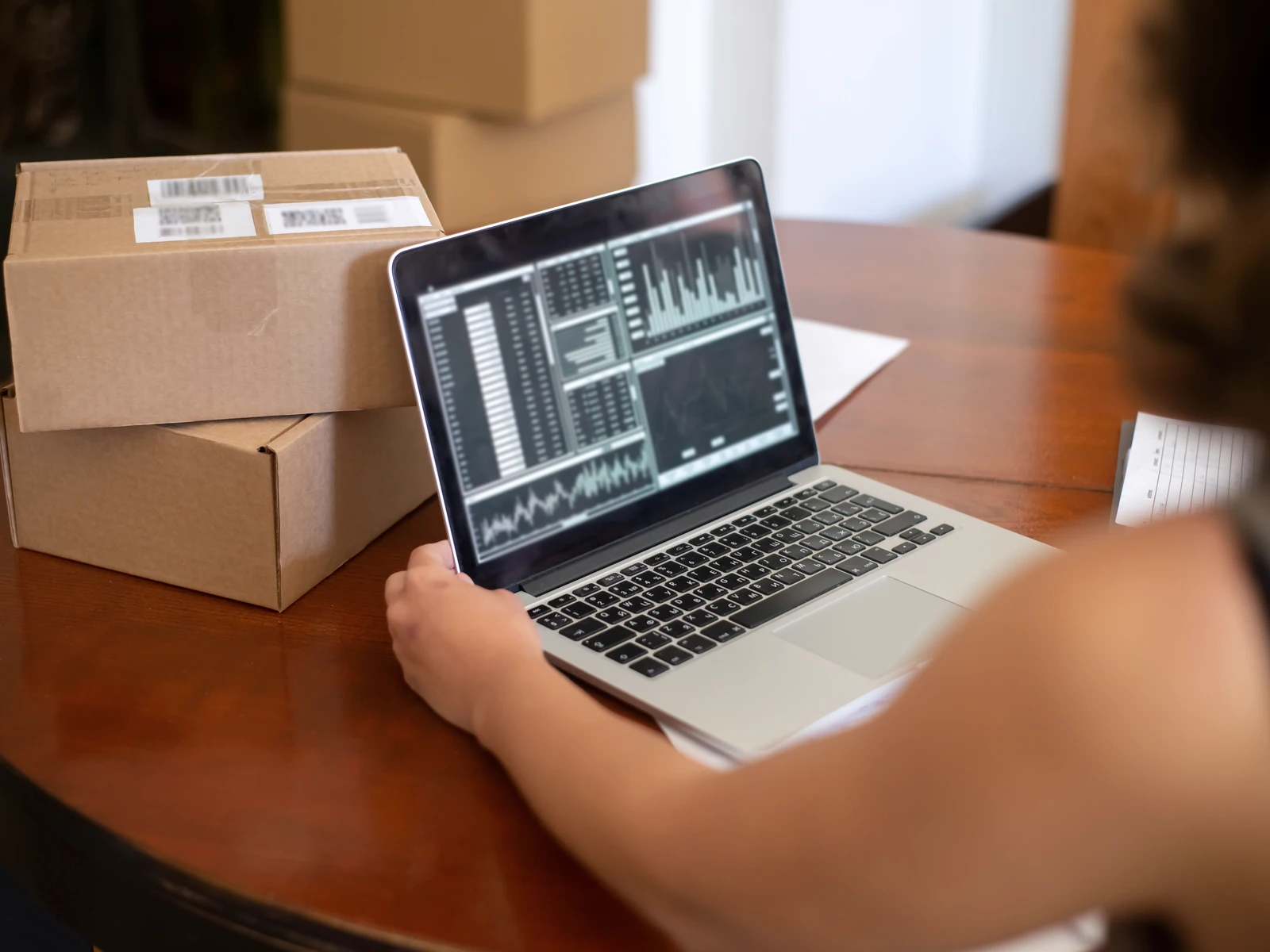 Arbeit am Laptop neben Geschäftsunterlagen und Paketen
